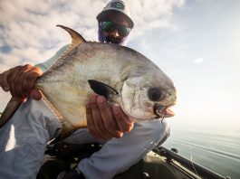 Man holds permit fish up to the camera from his fishing kayak in Key West, Florida