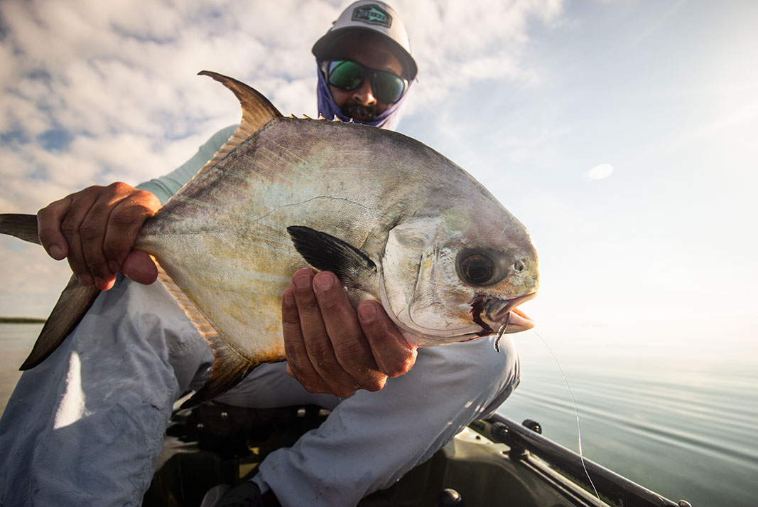 Alex Tejeda holds a fish close to the camera on his kayak in Key West, one of Google's most popular fishing destinations