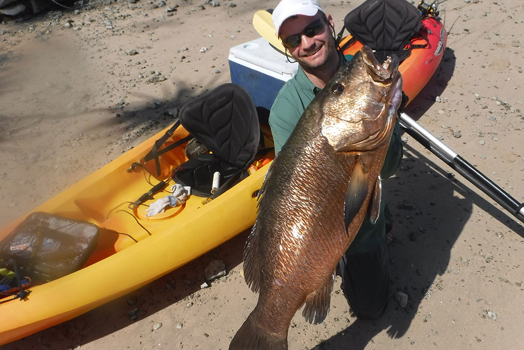 Man holds up a Pacific cubera snapper caught while kayak fishing in Costa Rica