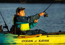A boy casts his kids fishing rod from an Ocean Kayak outfitted with fishing gear