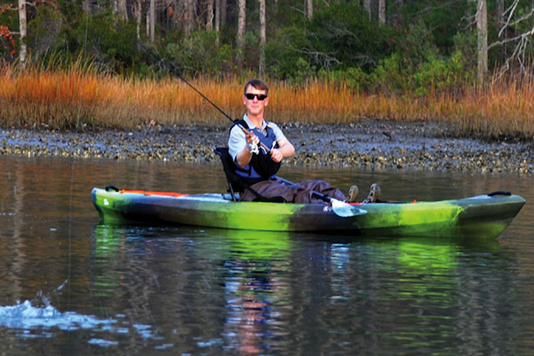 man casts fishing line from Perception Pescador Pro 120 fishing kayak