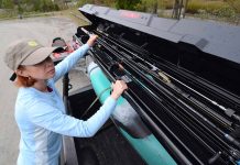 angler loading her fishing rods into storage rack on her truck