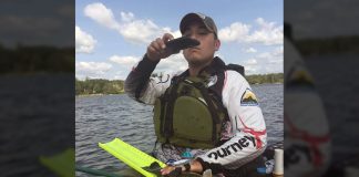 Man sitting on kayak taking a photo of his catch for an online fishing tournament