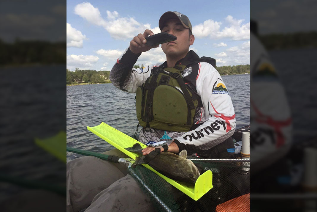 Man sitting on kayak taking a photo of his catch for an online fishing tournament