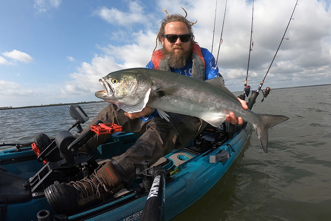 man holds up large fish on fishing kayak, captured with a camera on a RAM Mount