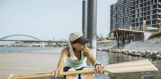 Woman stretching with a canoe paddle on a dock