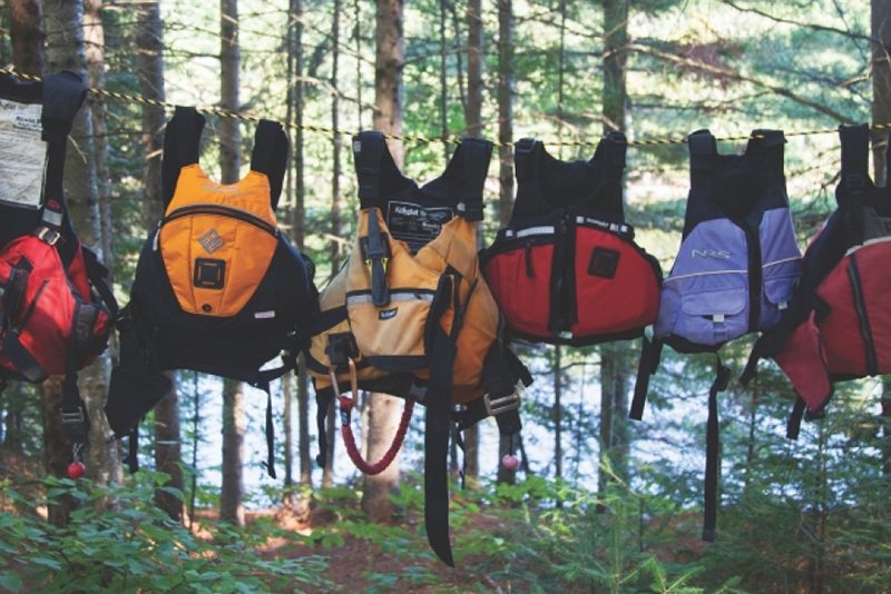 Old PFDs hang out on a line in the forest.