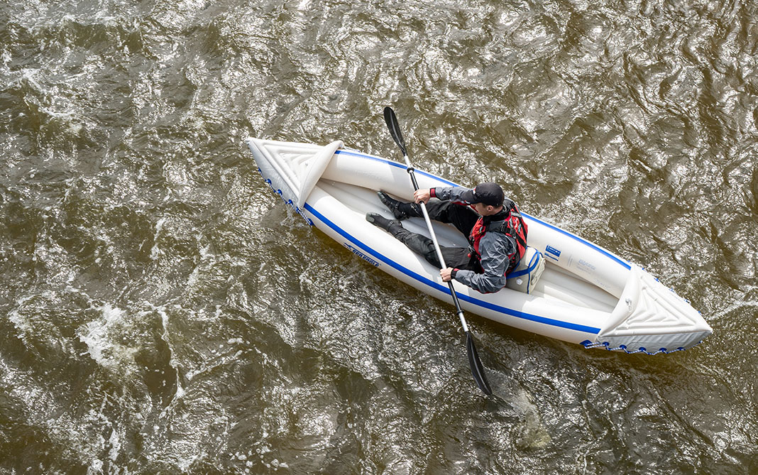 Blue and white inflatable kayak, with paddler on the water