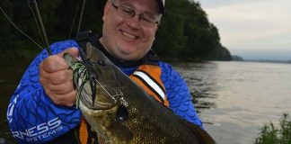 angler holds up a smallmouth bass caught while fishing in muddy water