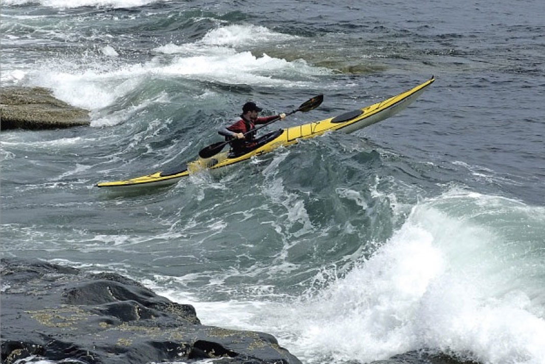 sea kayaker launches in ocean surf