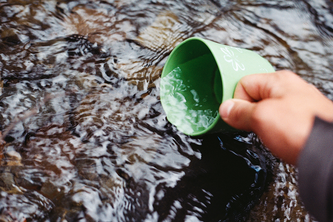 Person scooping up water using a green cup | Photo by Jens Johnsson from Pexels