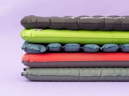 Various colors of sleeping pads stacked on top of one another