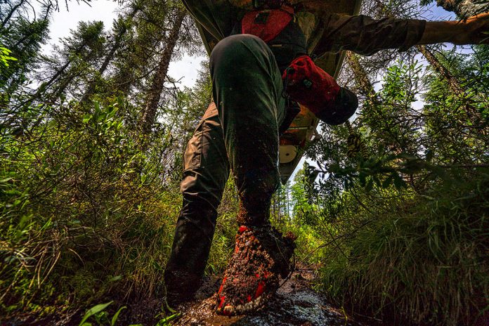 Person carrying canoe through the mud