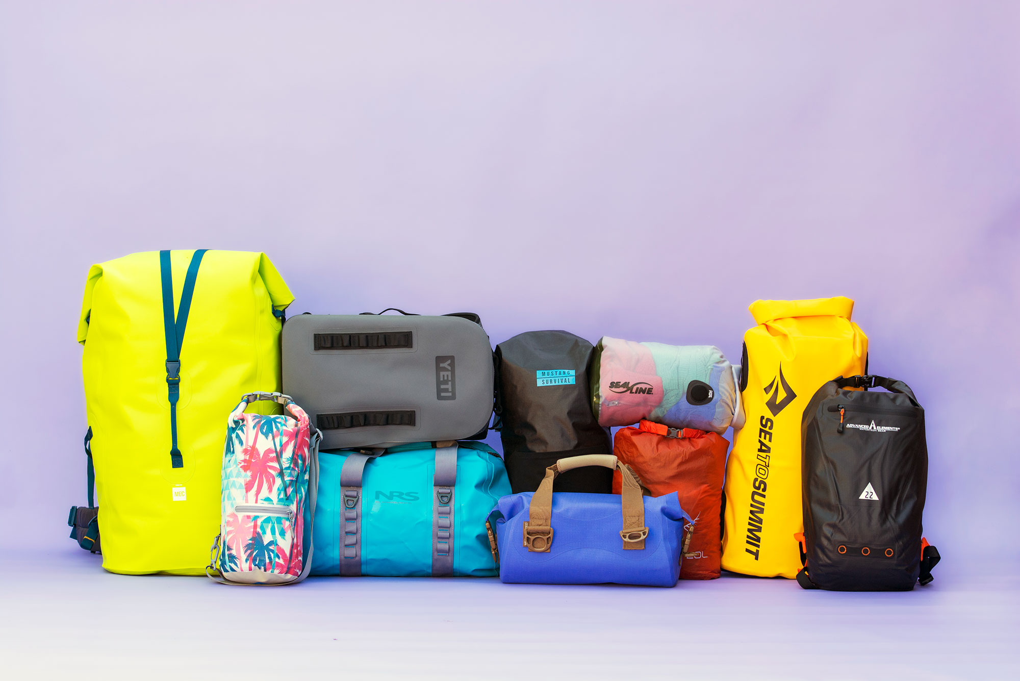 Drybags in a variety of sizes and colors stacked on one another.