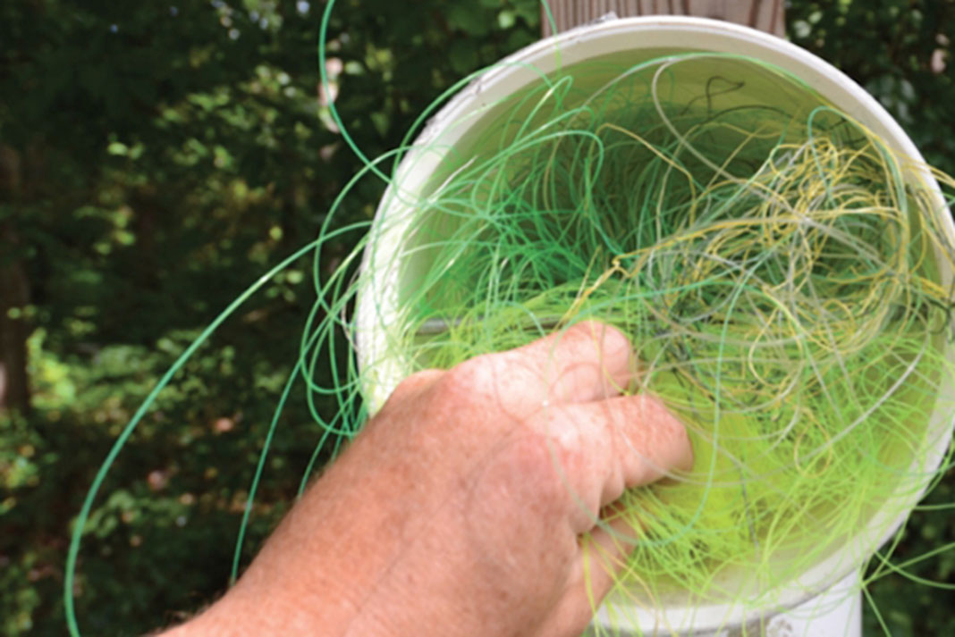 a person puts used fishing line in a bucket to conserve their favorite fishing spot