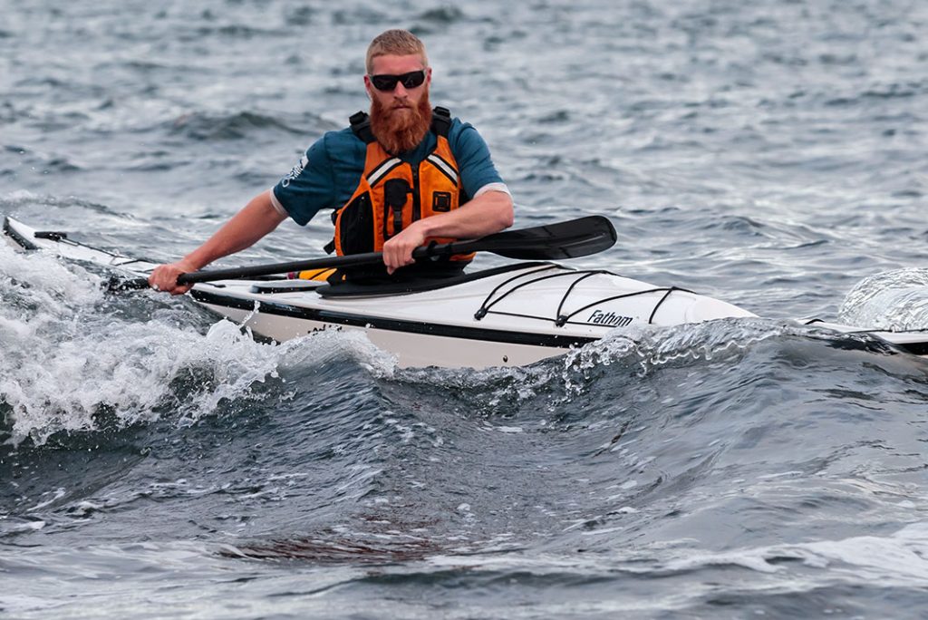 Man cresting a wave in a sea kayak