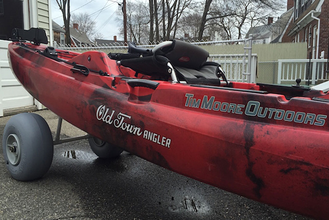 A red Old Town Fishing Kayak sits outside on a homemade kayak beach cart