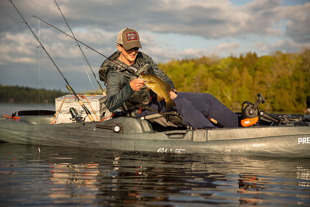 man catches smallmouth bass while kayak fishing in the fall