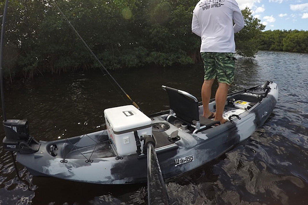 man stands up and fishes from the Kaku Kayaks Wahoo 12.5 hybrid fishing boat