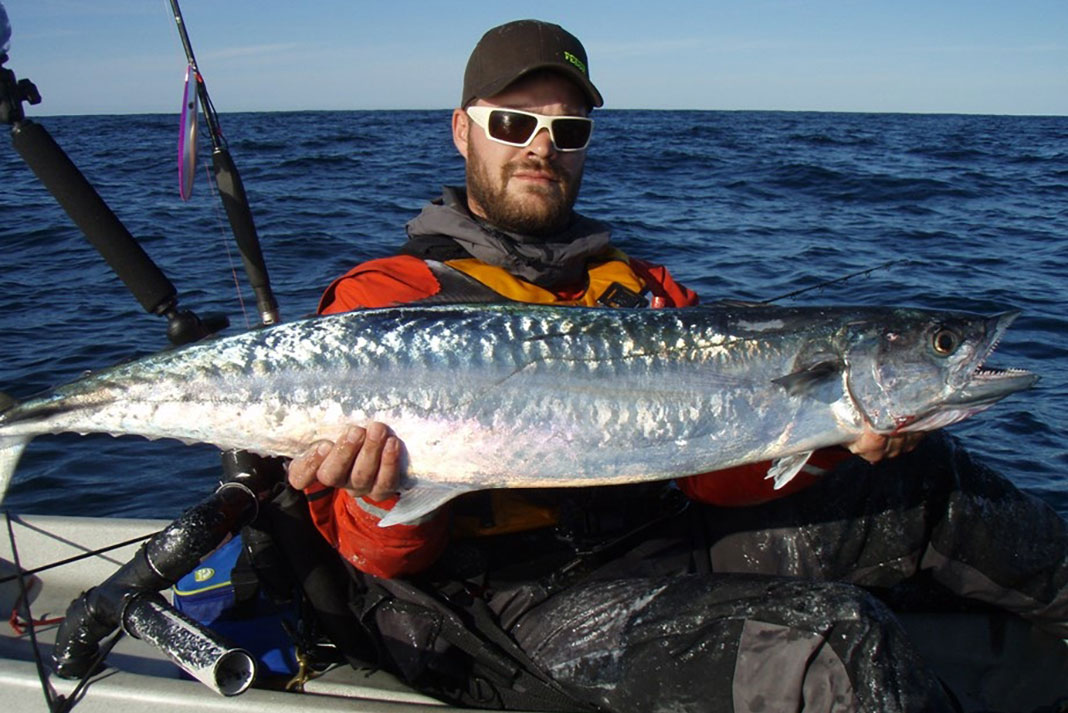 angler holds up a smoker king mackerel caught on a fishing kayak