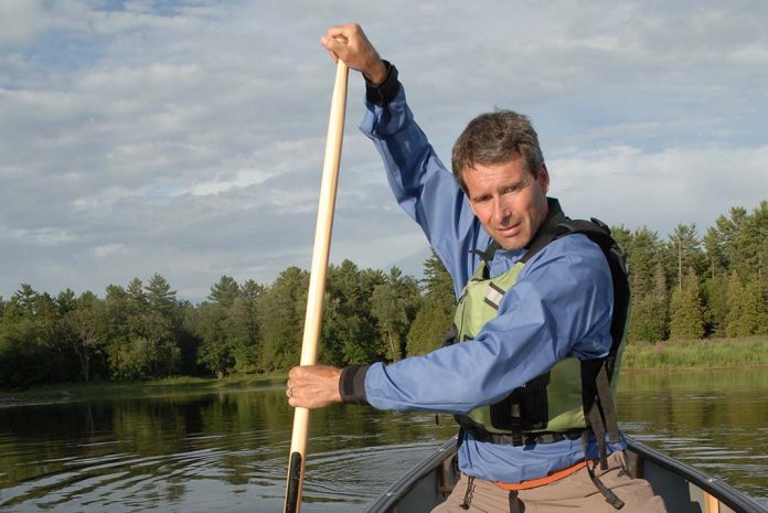 man in a canoe demonstrates the cross-forward stroke