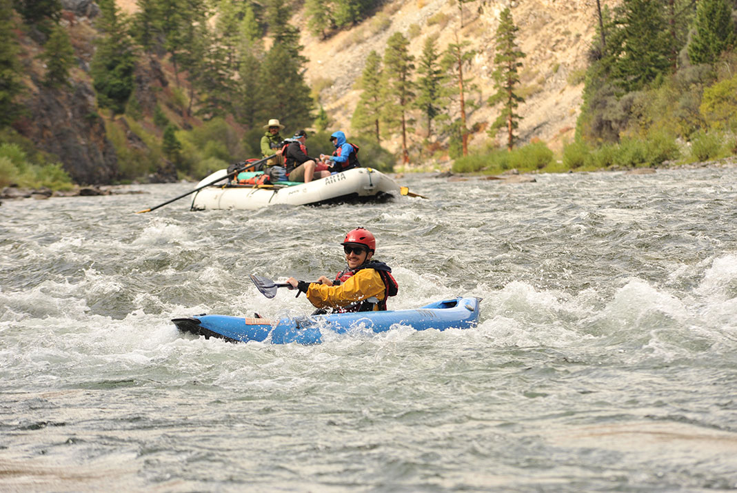 Raft in background and kayaker in foreground.