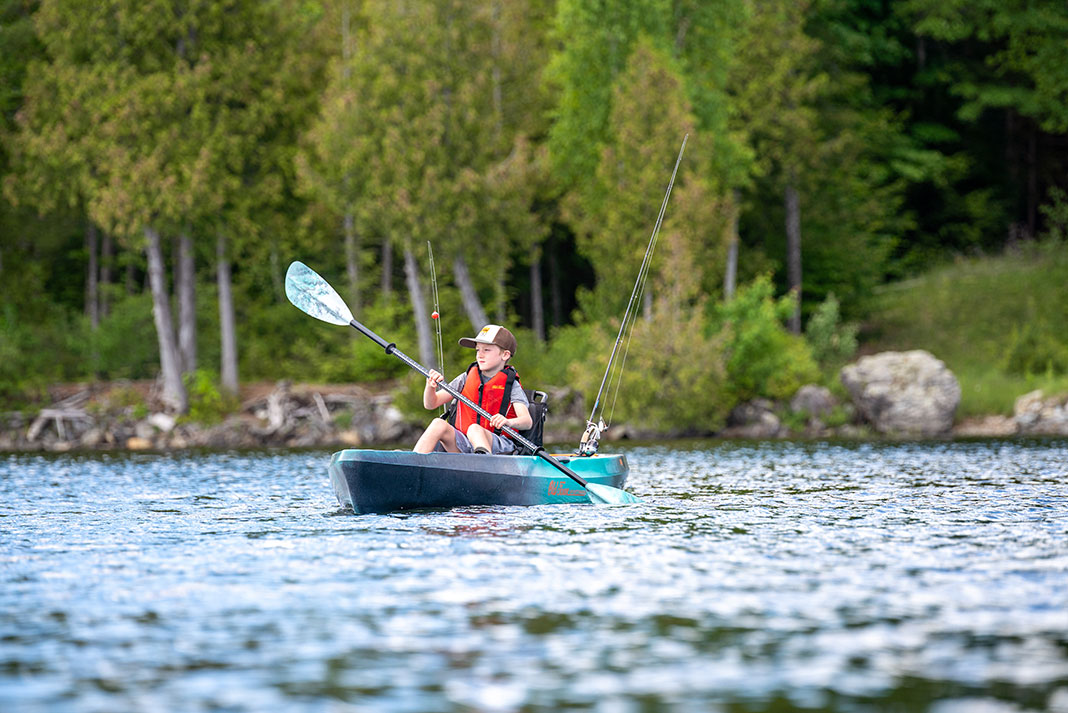 boy paddles a fishing kayak