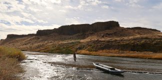 angler uses an inflatable tandem kayak to fish a low water fall river