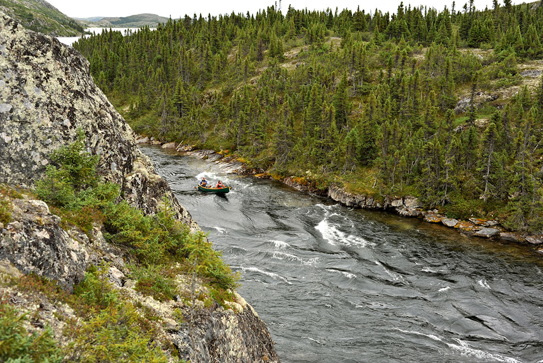 Canoe heading down wavy river.