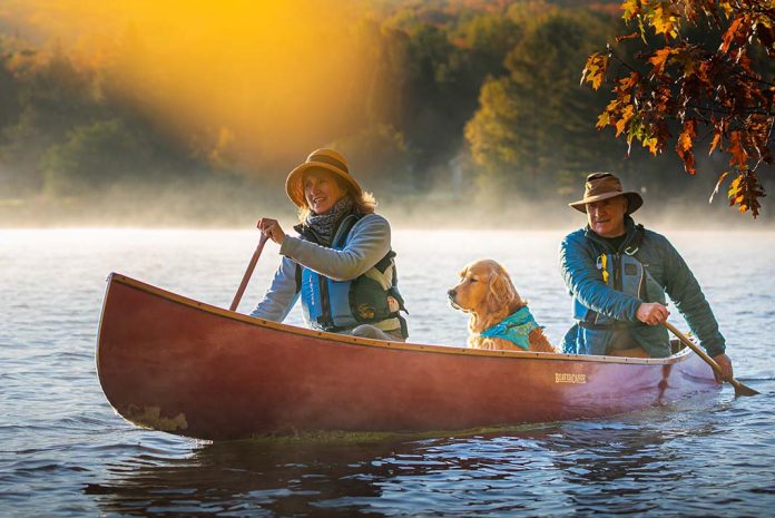 man, woman and dog paddle in a well maintained cottage canoe