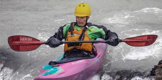 male whitewater kayaker uses a boof technique to kayak over small drops