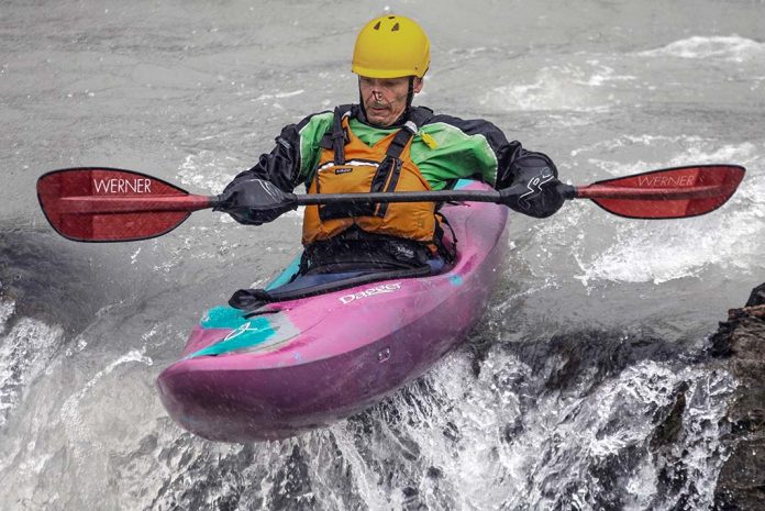 male whitewater kayaker uses a boof technique to kayak over small drops