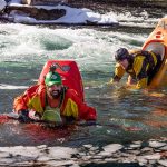 Learn The Bow Stall Kayak Technique two male whitewater kayakers demonstrate the kayak bow stall in an icy river