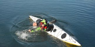 man demonstrates how to sweep roll a kayak