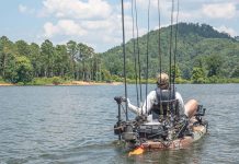 man pilots motorized fishing kayak on a lake