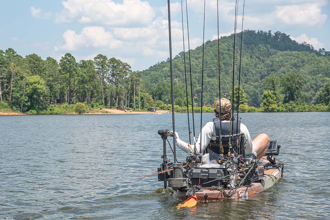 man pilots motorized fishing kayak on a lake