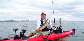 kayak angler holds up a walleye caught while fishing in the fall