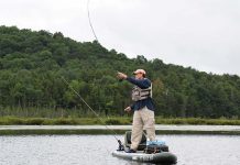 kayak angler stands and casts at Lake Oseetah in New York's Adirondack Mountains