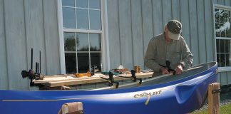 man installs wood gunwales on his canoe