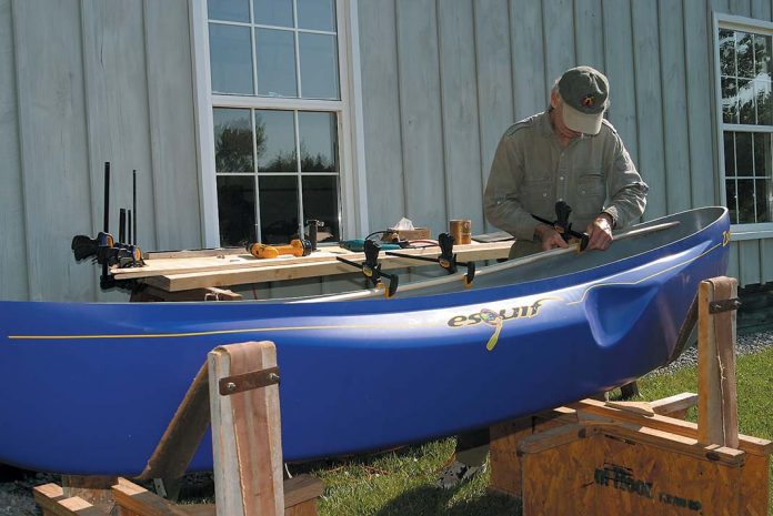 man installs wood gunwales on his canoe