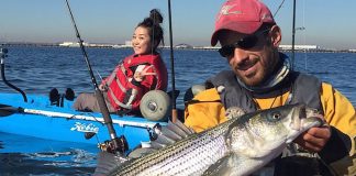 kayak fishing guide Elias Vaisberg holds up a striped bass