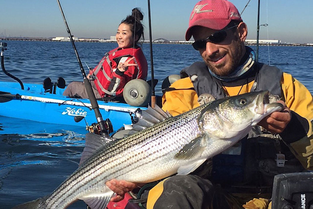 kayak fishing guide Elias Vaisberg holds up a striped bass