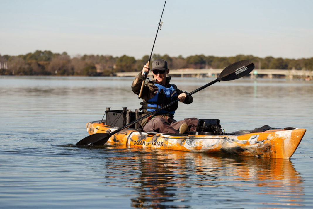 man paddles backwards in a fishing kayak