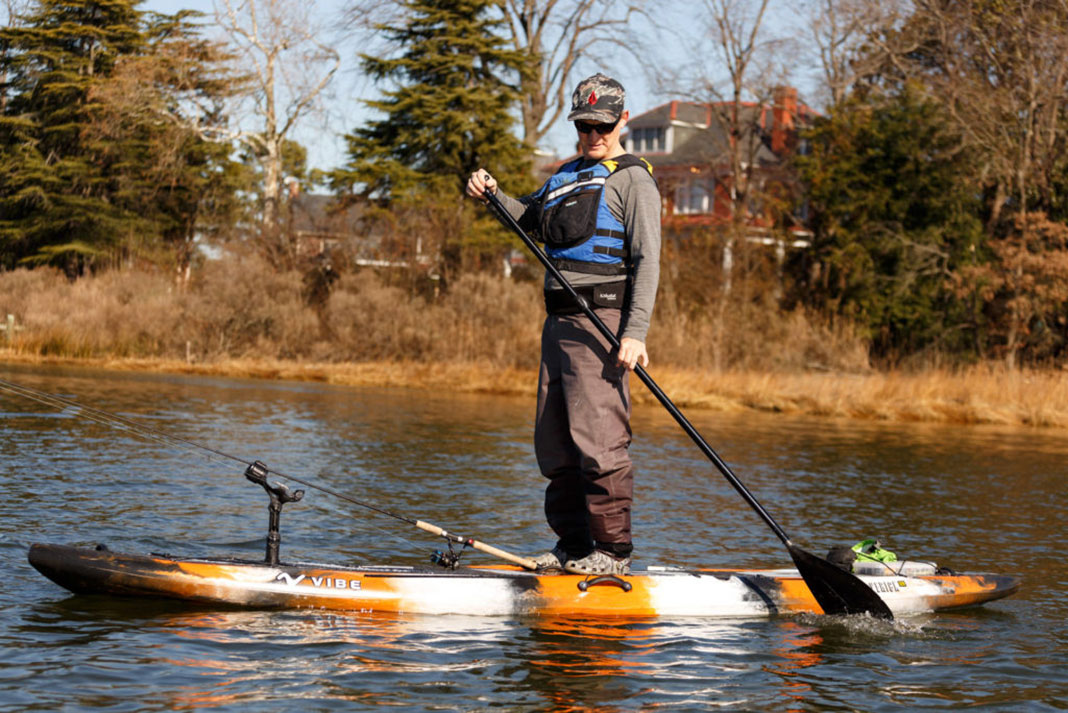 man stands and paddles backwards on a SUP