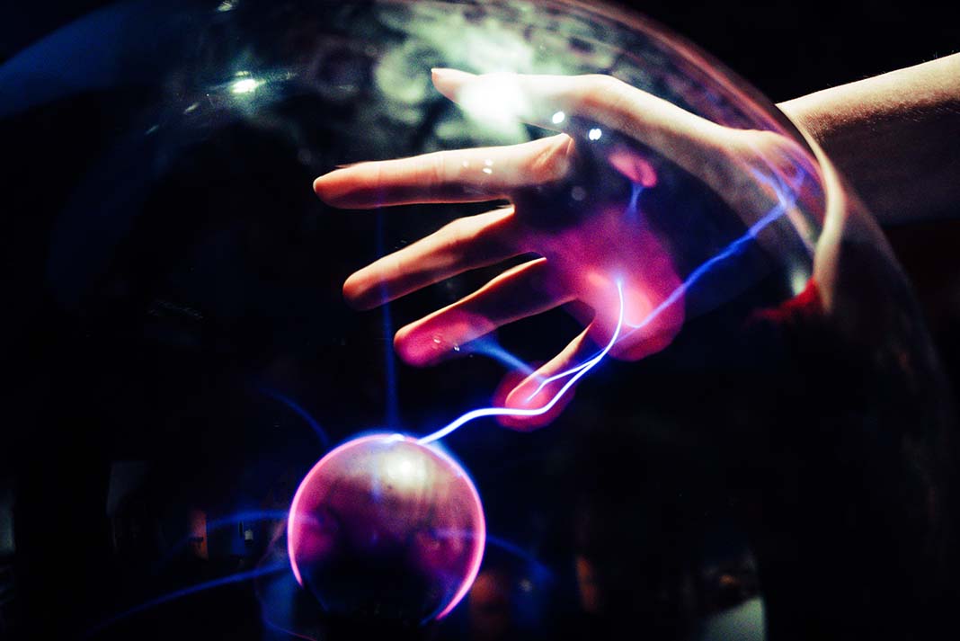 a hand reaches out to a Tesla plasma ball