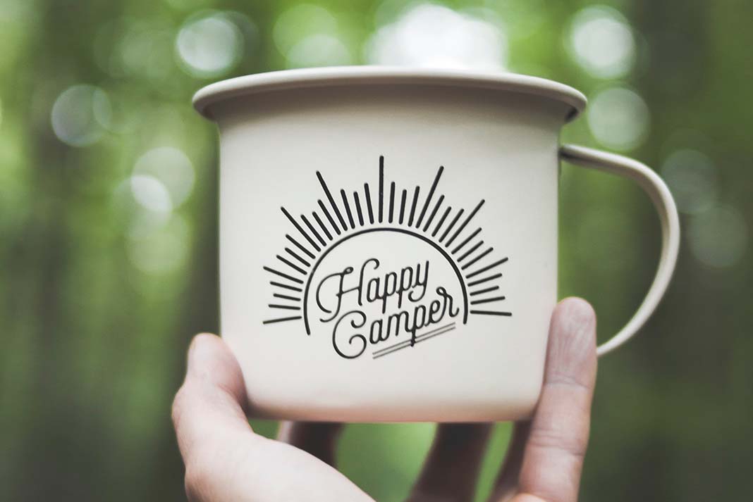 Person holds up a happy camper mug