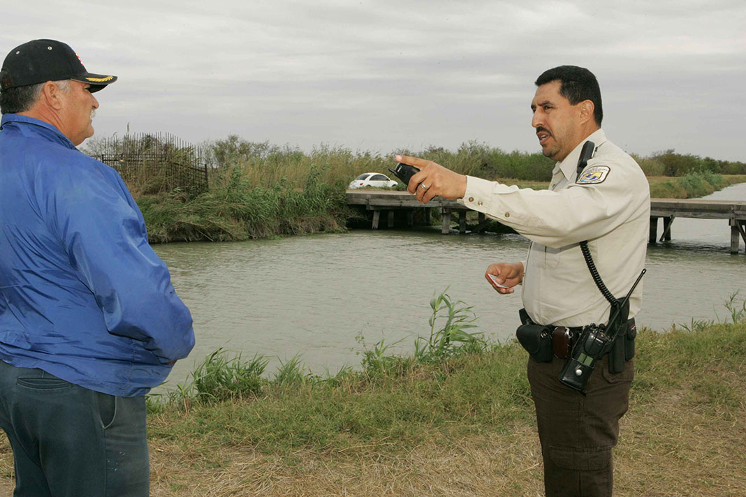 a conservation officer checks a man's fishing license by the riverbank