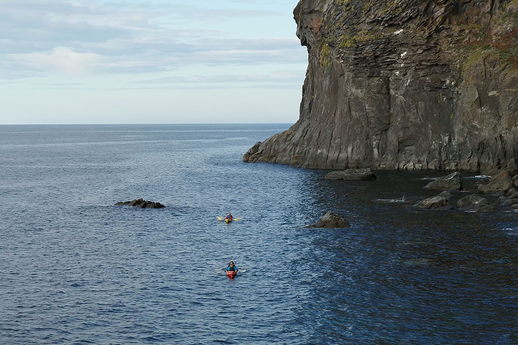 Kayak paddles next to towering cliff