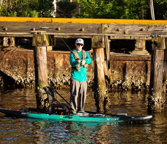 man stands and fishes from the Vibe Cubera 120 Hybrid fishing kayak paddleboard hybrid