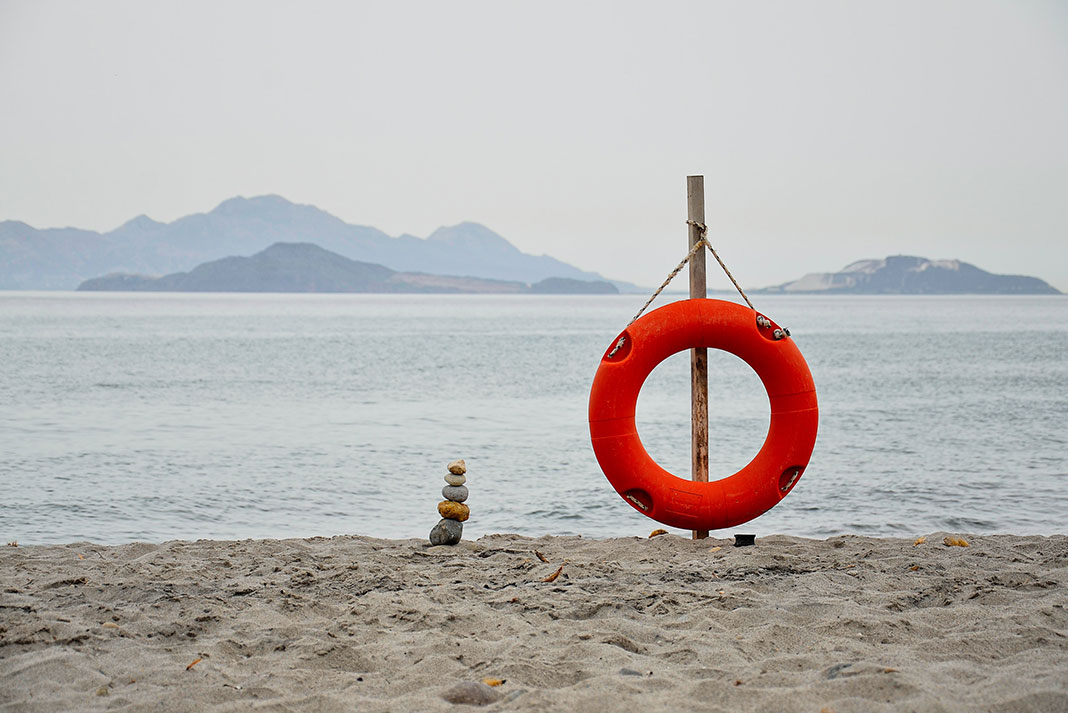 an orange life-saving buoy on a beach, an example of safety gear